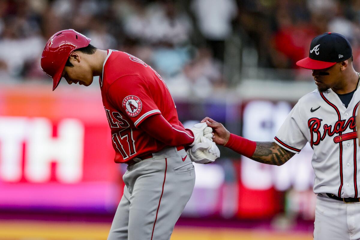 Braves second baseman Orlando Arcia checks out a glove worn by the Angels' Shohei Ohtani at second base July 23, 2022.