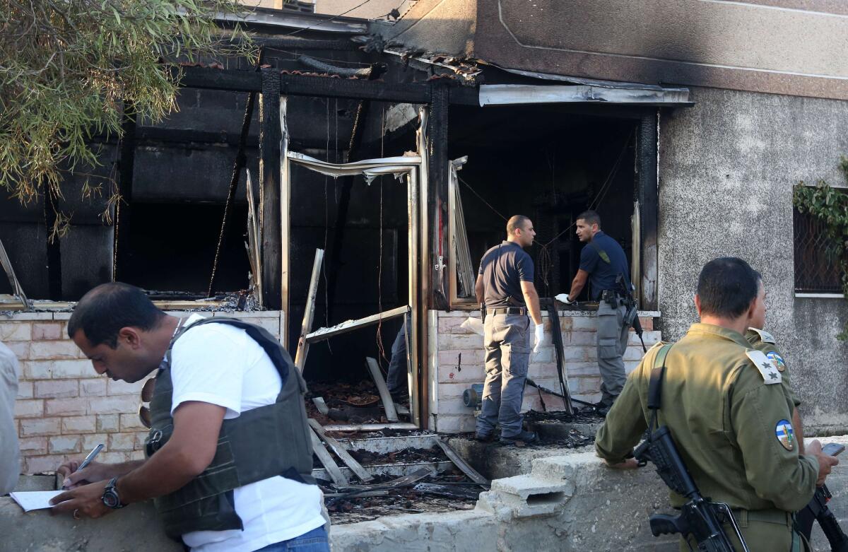 Israeli forces inspect a Palestinian house that was set on fire in the West Bank village of Duma, killing a child, on July 31.