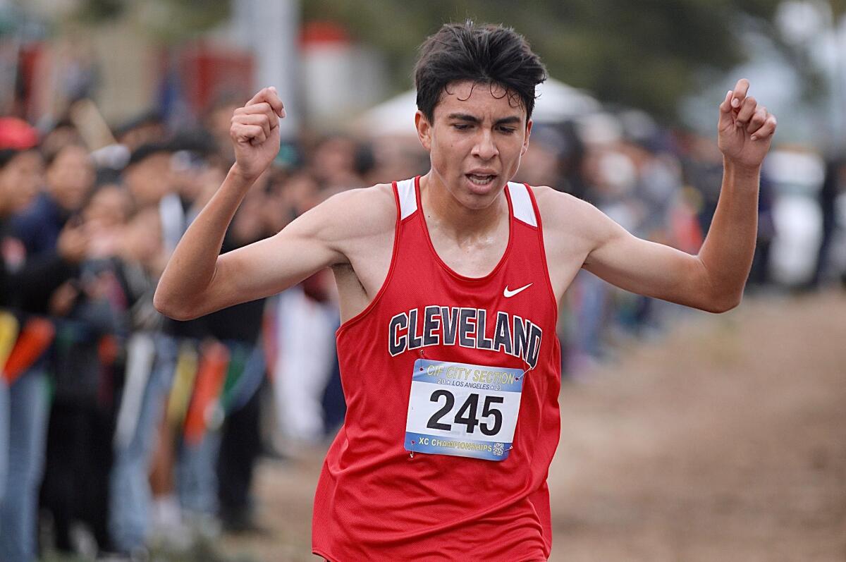Cleveland's Joseph Vargas raises his arm in triumph after winning the City Section Division I cross-country boys' race title.