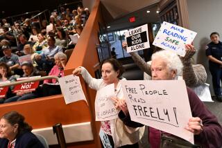 Huntington Beach, California October 17, 2023-Opponents of the book ban issue hold signs during a Huntington Beach city council meeting Tuesday night. (Wally Skalij/Los Angeles Times)