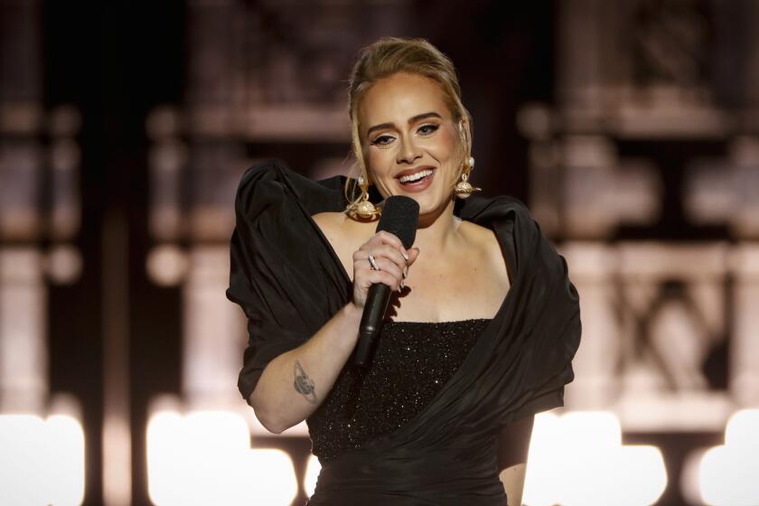 A woman wearing a black dress and smiling into a microphone