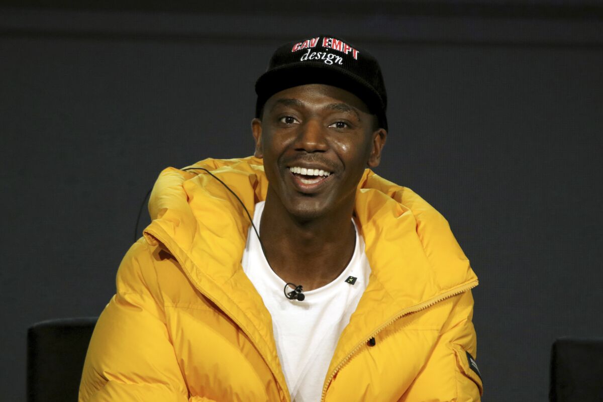 A man in a yellow puffer jacket and a baseball cap smiles broadly