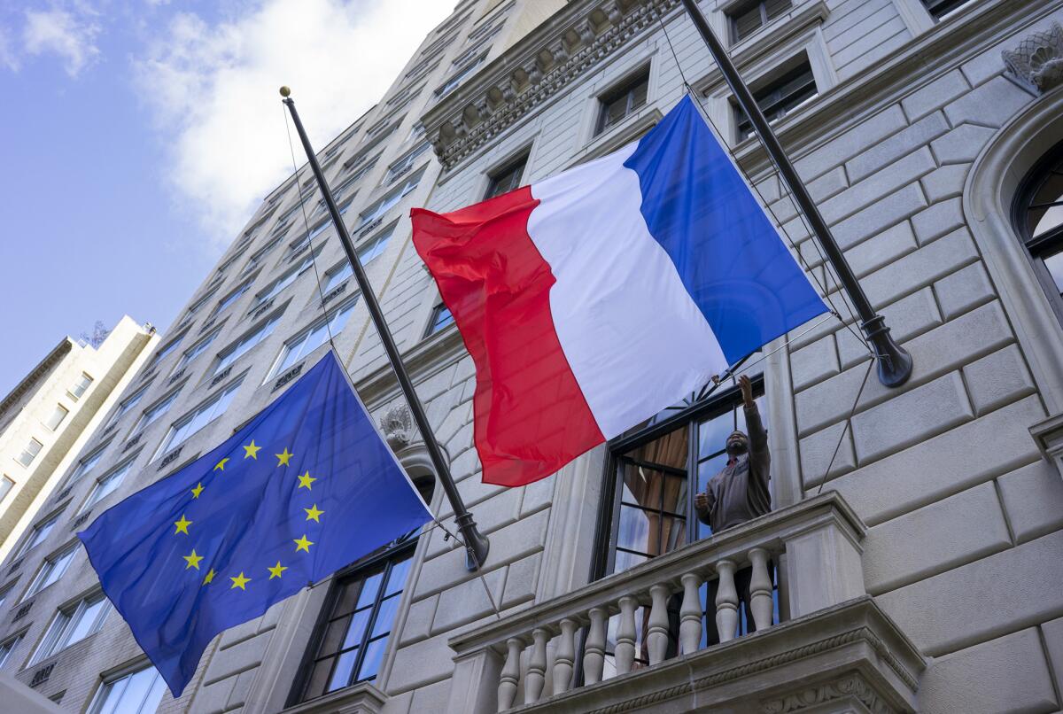 La bandera de Francia, a la derecha, ondea a media asta en el consulado francés en Nueva York. A la izquierda aparece la bandera de la Unión Europea.
