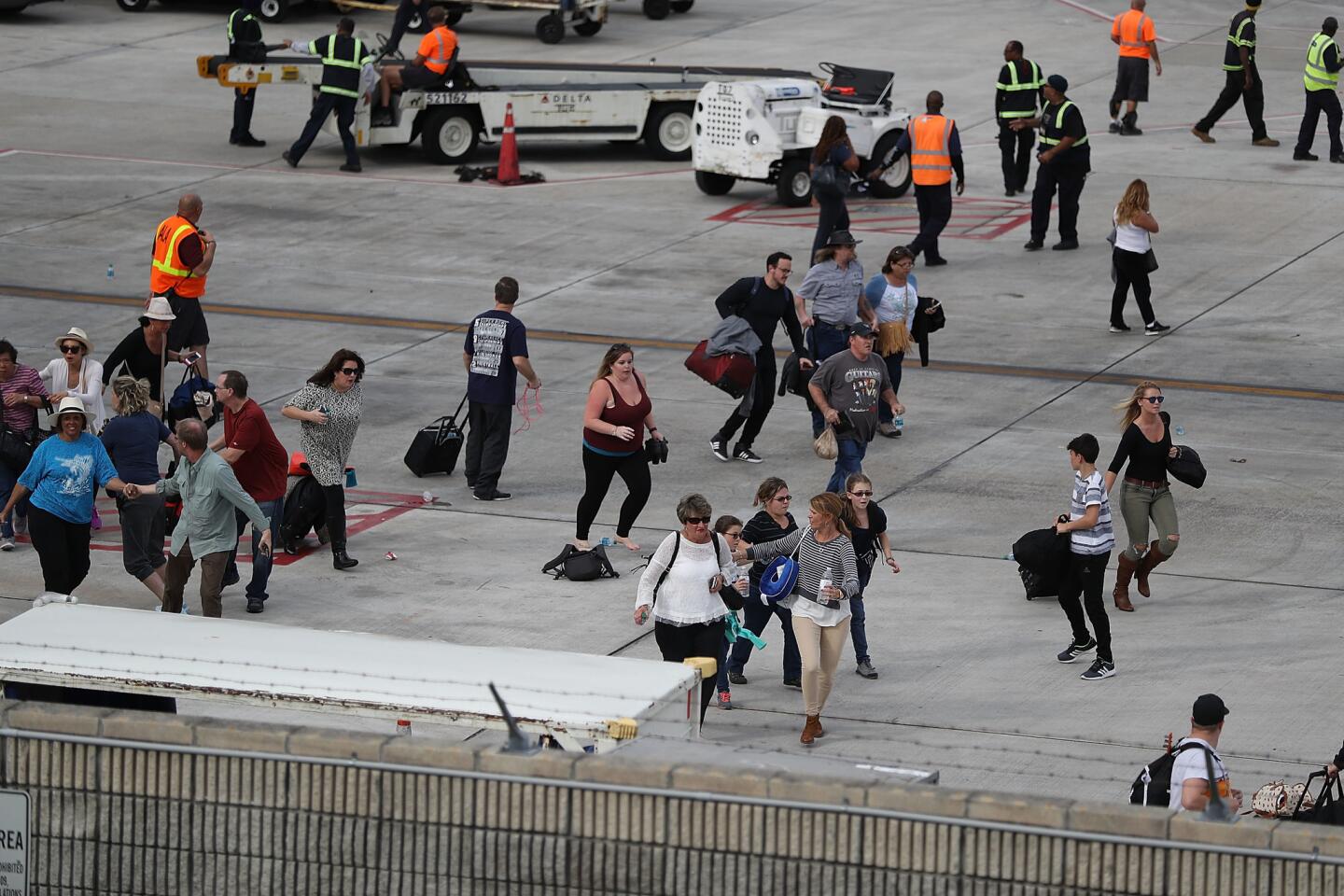 People seek cover on the tarmac of Fort Lauderdale-Hollywood International Airport after a shooting took place near the baggage claim.