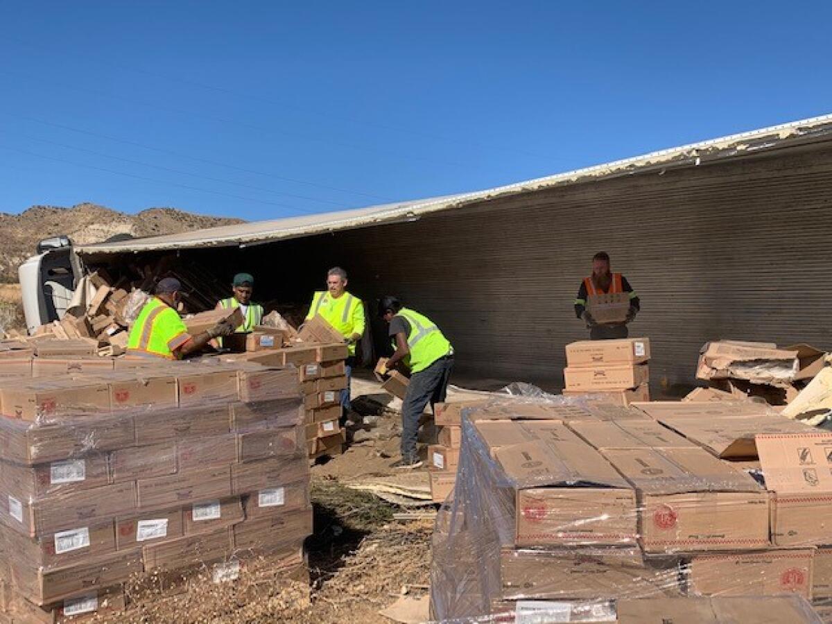 Caltrans crews help clean up hundreds of boxes of cookie dough alongside the Cajon Pass on Thursday.