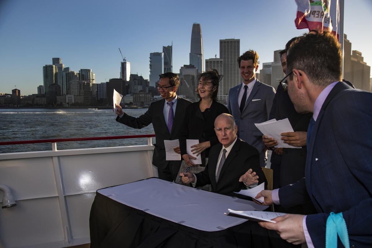 Gov. Jerry Brown signs bills addressing climate change aboard an electric-powered boat with San Francisco in the background after the Global Climate Action Summit on September 13, 2018.