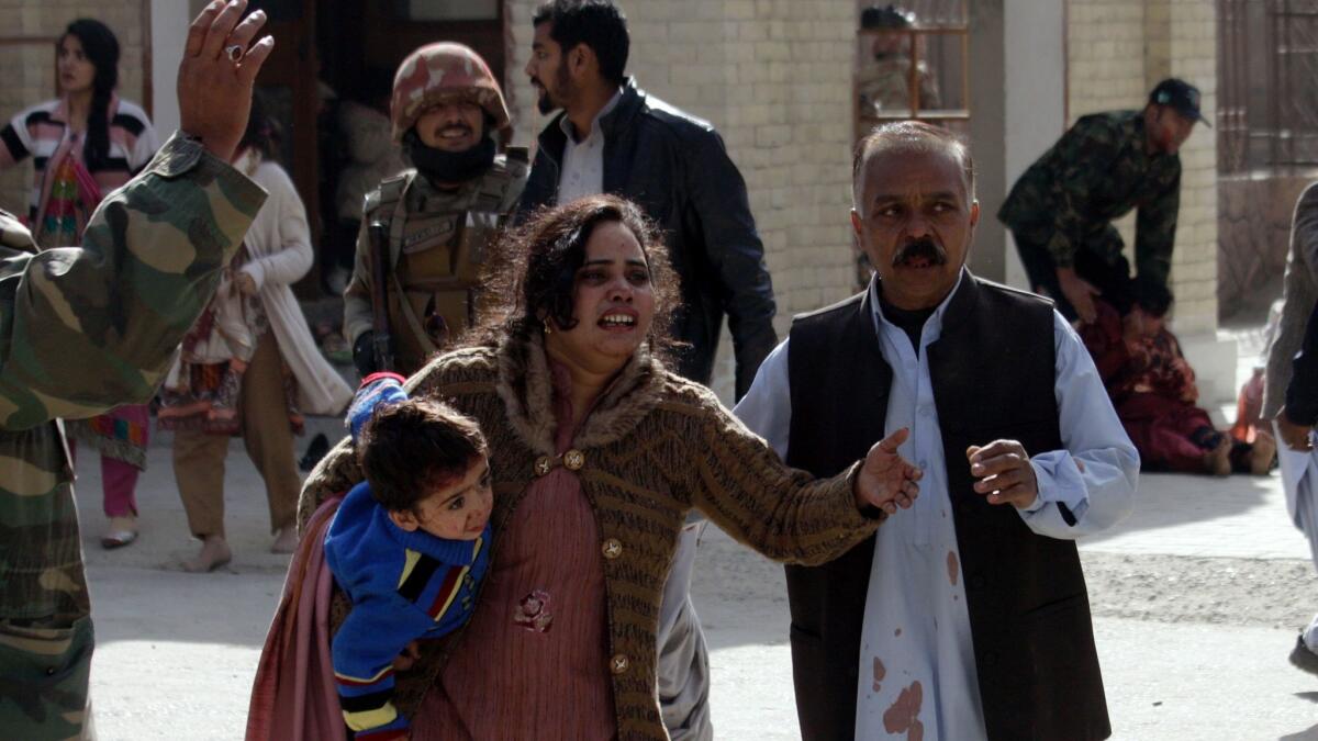 A man helps an injured woman and a child after an attack on a church in Quetta, Pakistan.