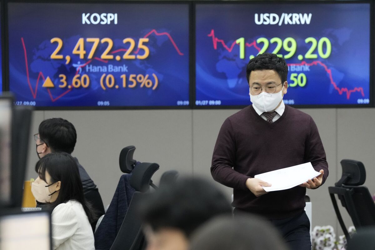 A currency trader passes by the screens showing the Korea Composite Stock Price Index (KOSPI), left, and the foreign exchange rate between U.S. dollar and South Korean won at the foreign exchange dealing room of the KEB Hana Bank headquarters in Seoul, South Korea, Friday, Jan. 27, 2023. Asian shares advanced Friday, tracking a rally on Wall Street following reports suggesting the economy and corporate profits may be doing better than feared. (AP Photo/Ahn Young-joon)