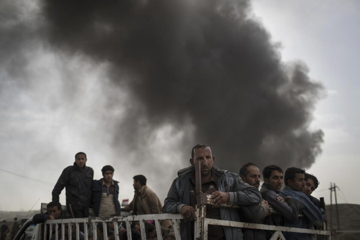 Displaced residents stand on the back of a truck at a checkpoint Nov. 1 near Qayara, south of Mosul, Iraq.