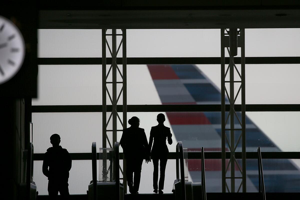 People are silhouetted against an airport window.