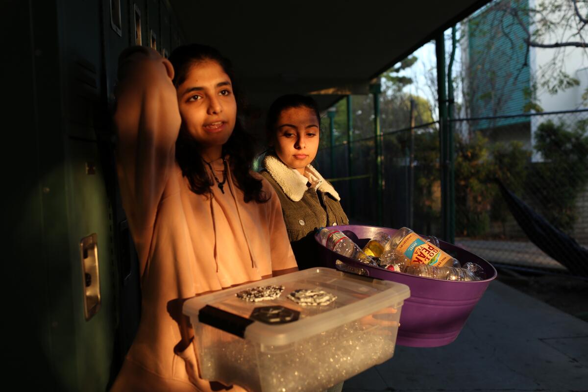 Coral Ben-Aharon, left, and Sarah Ali carry recycled plastic they are using for a project at Granada Hills Charter High School on Dec. 13 in Los Angeles. Chemistry teacher and science club advisor Jeanette Chipps incorporates climate change into her curriculum and projects.