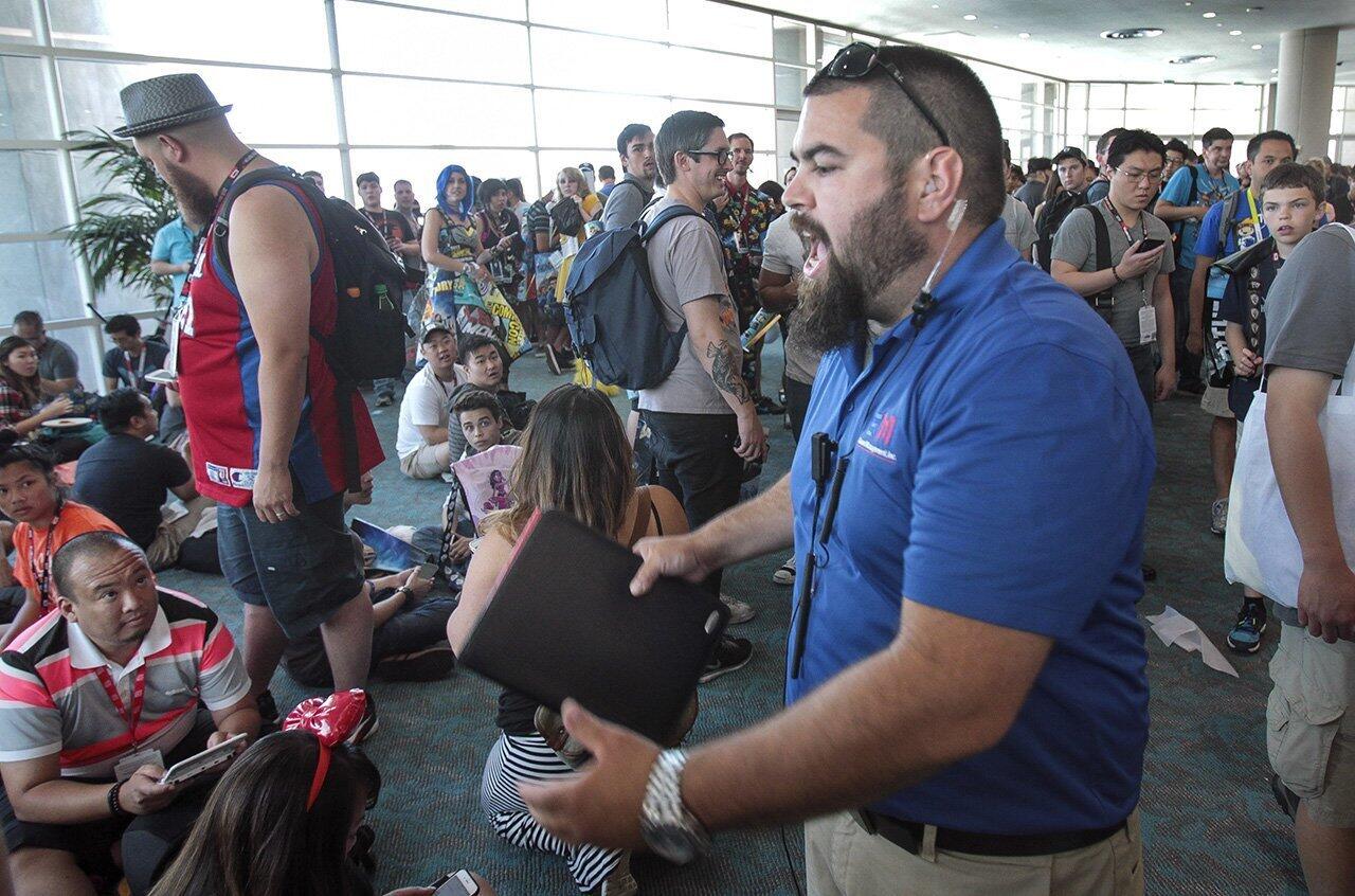 A security guard yells at a large crowd, who have gathered on a rumor of being able to capture a rare Pokemon being released from the Pokemon Go panel going on in Hall H directly below them, to move during Comic-Con.