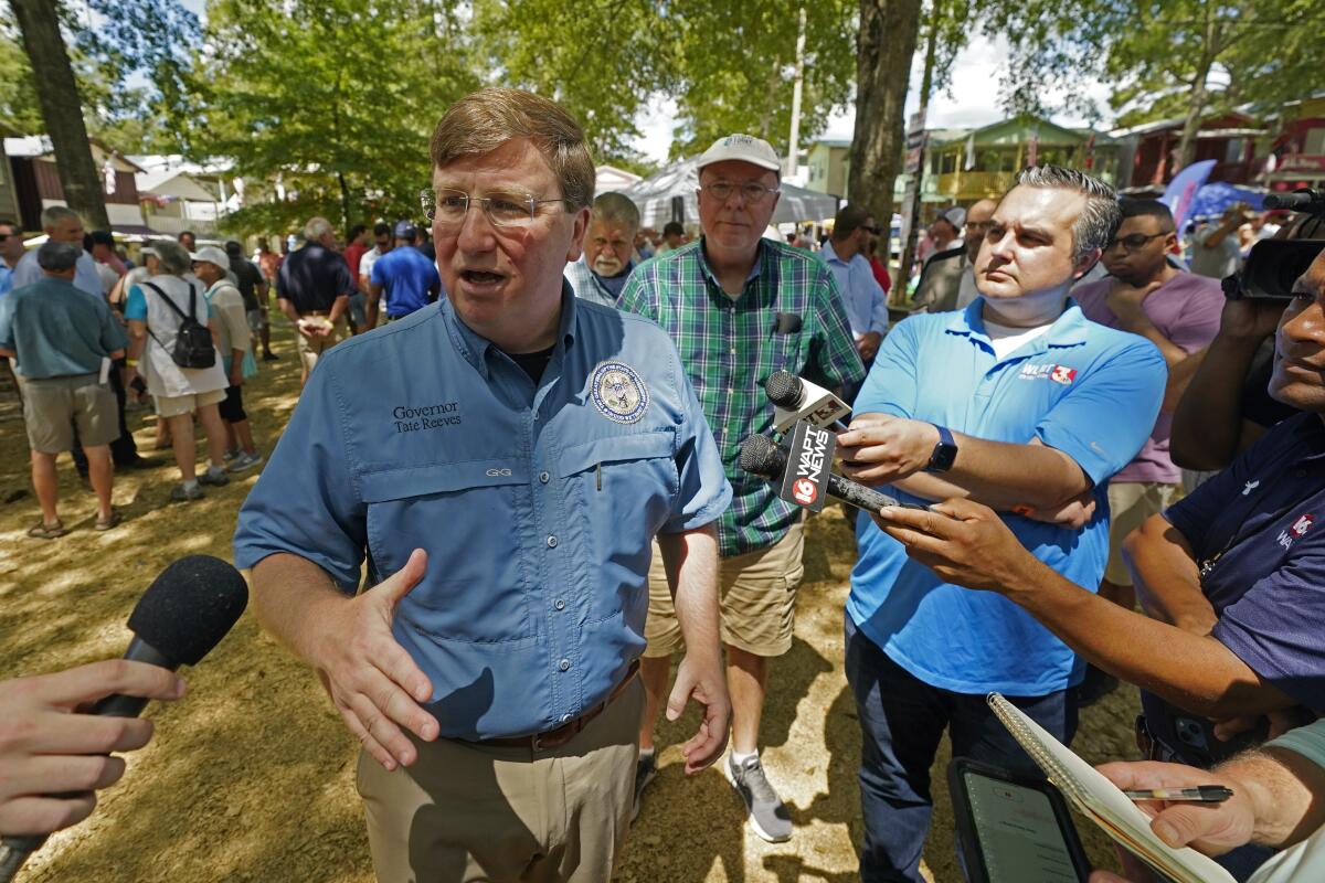 Republican Gov. Tate Reeves speaks with reporters after his address at the pavilion in Founders Square at the Neshoba County Fair in Philadelphia, Miss., Thursday, July 28, 2022. The fair, also known as Mississippi's Giant House Party, is an annual event of agricultural, political, and social entertainment at what might be the country's largest campground fair. (AP Photo/Rogelio V. Solis)