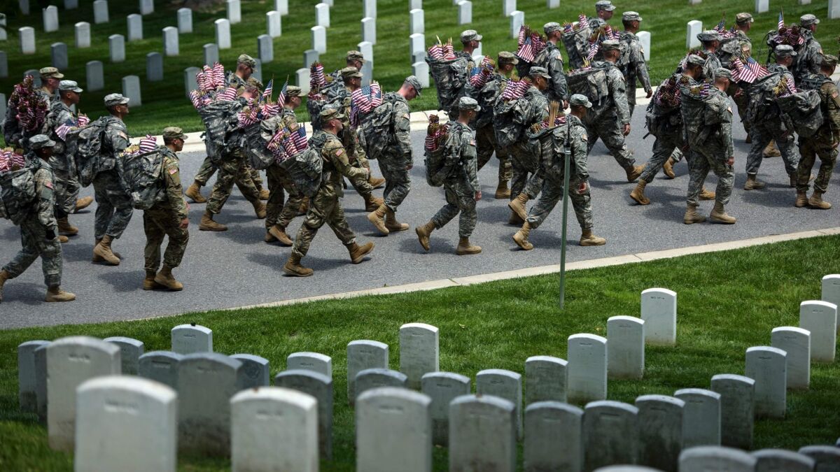 U.S. Army soldiers last year marched with miniature American flags that were placed at graves in Arlington National Cemetery in Virginia. (Brendan SmialowskiI / AFP/Getty Images)