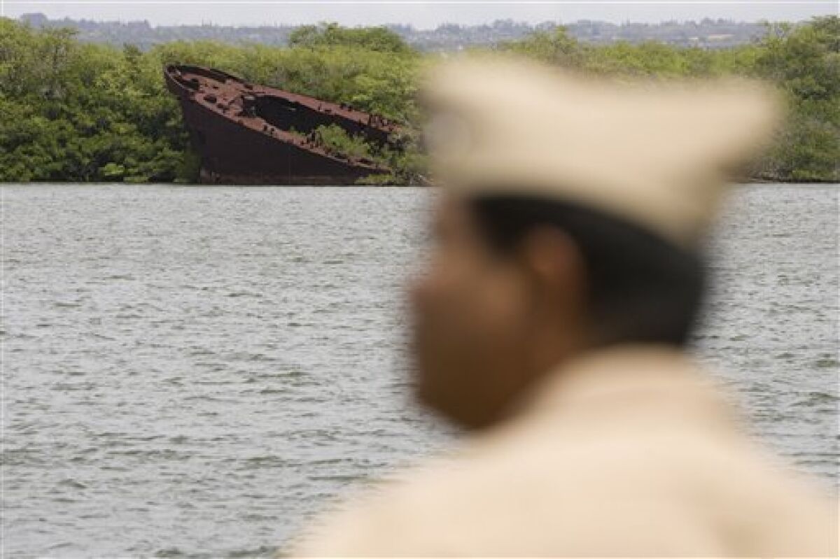 A naval official stands in a ship across from the remains of the USS LST-480, or Landing Ship Tank, in West Loch near Pearl Harbor, Monday, April 20, 2009, in Honolulu. The naval vessel sank in an accidental explosion on May 21, 1944 which killed 163 men and sank several other Landing Ship Tank vessels. The LST ships were being loaded with ammunition and gas and were preparing for a voyage to the Marianas Islands, for what was expected to be a brutal invasion, codenamed "Operation Forager." The Navy will commemorate the 65th anniversary of the disaster on Thursday, May 21, 2009. (AP Photo/Marco Garcia)