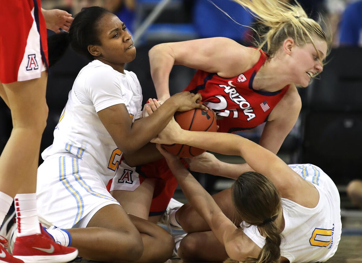 UCLA’s Charisma Osborne, left, and Chantel Horvat, right, fight for the ball with Arizona’s Cate Reese during the Bruins' win Sunday.