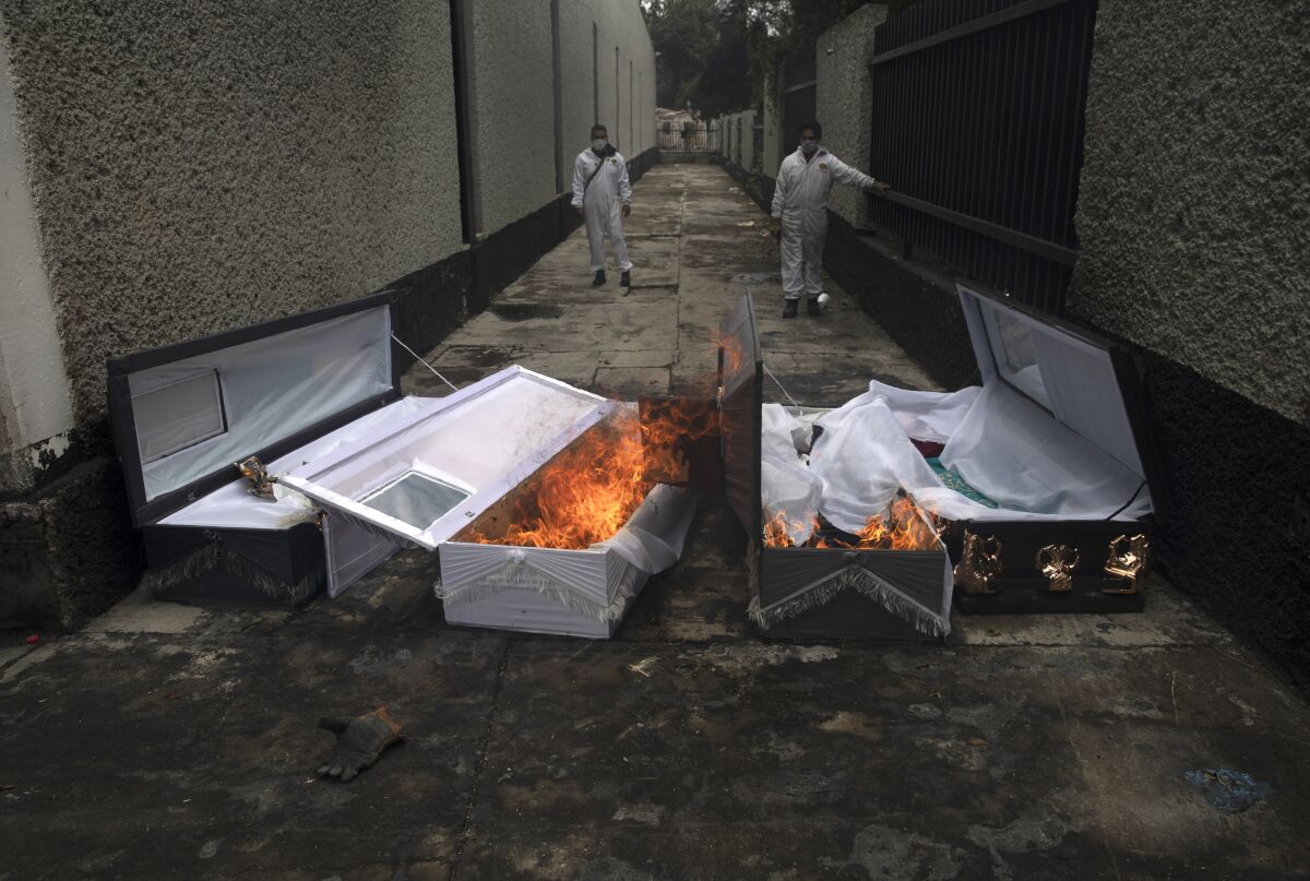 Coffins of COVID-19 victims burn after cremation at a Mexico City cemetery.