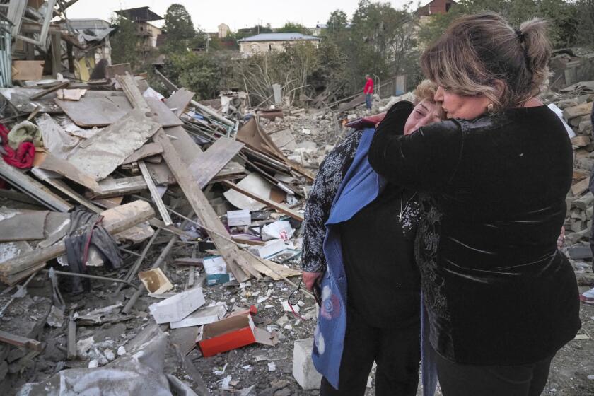 Homeowner Lida Sarksyan is comforted by a neighbor after her home was destroyed by shelling.