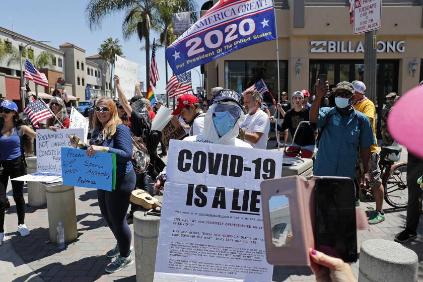 Demonstrators crowd the intersection at Main Street and Walnut Avenue in downtown Huntington Beach on Friday protesting against social distancing and the economic shutdown.