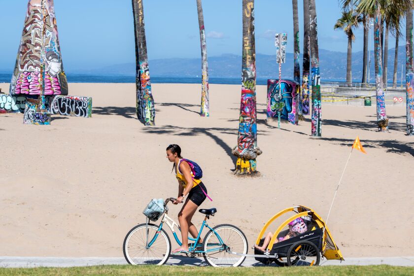 A person bikes despite the bike path being closed in Venice Beach, california on the first day Los Angeles County allowed beaches to reopen after a six-week closure implemented to stop the spread of the coronavirus (Covid-19),on May 13, 2020. - The County only allows activities such as running, walking, swimming and surfing with sunbathing and volleyball not allowed. (Photo by VALERIE MACON / AFP) (Photo by VALERIE MACON/AFP via Getty Images)