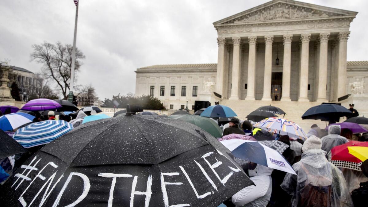 A pro-abortion rights supporter holds an umbrella that reads "#EndTheLies" during a rally outside the Supreme Court in Washington.