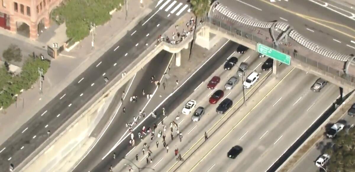 People stand on a freeway, blocking approaching vehicles.