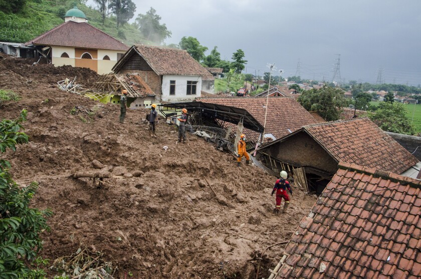 Rescuers search for victims at a village hit by Sunday's landslides in Sumedang, West Java, Indonesia, Monday, Jan. 11, 2021. Landslides triggered by heavy rain in the village left at a number of people died and injured, officials said. (AP Photo/Sorasoca)