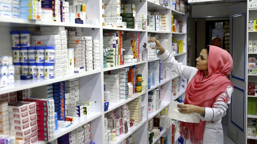 A drugstore employee picks medicine from a shelf in downtown Tehran.