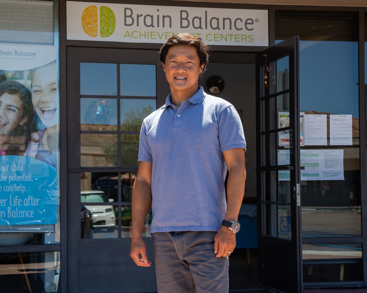 Jon Pak, standing outside in the sun in front of Brain Balance of San Diego, smiling at the camera. 