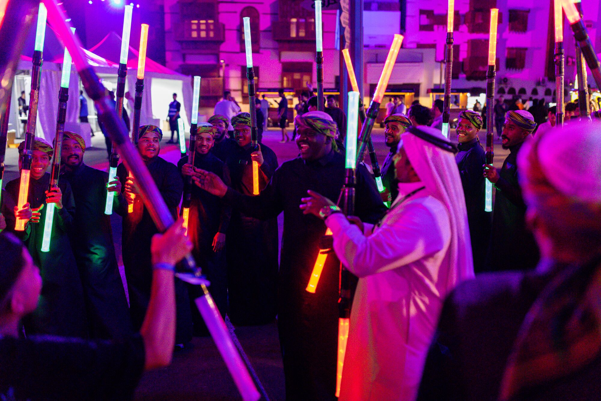 Men dancing with glow sticks at a nighttime music festival.