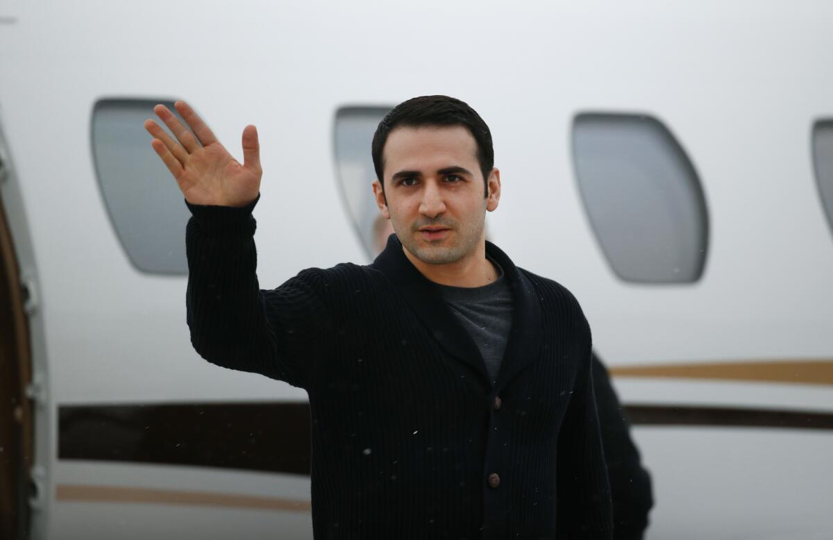 Amir Hekmati waves after arriving on a private flight 
