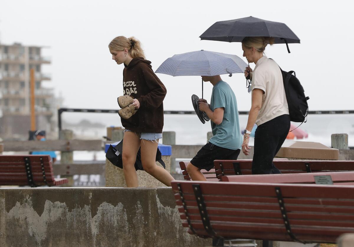 A family packs up and heads for home as rain begins to fall downtown at Main Beach on Friday in Laguna Beach.