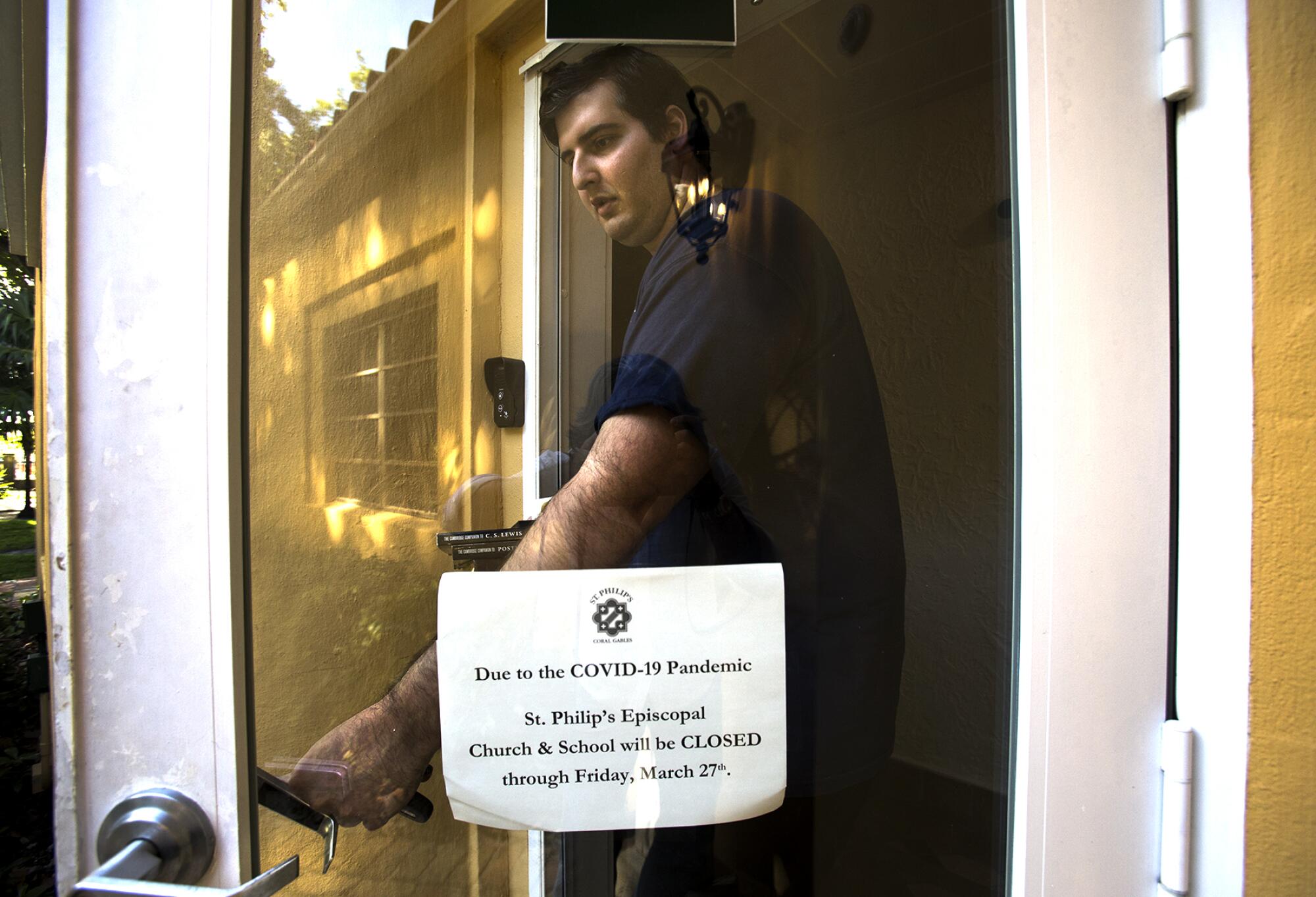 The Rev. Michael Sahdev takes books and holy water from his office at the church, which closed to help contain the spread of the coronavirus.