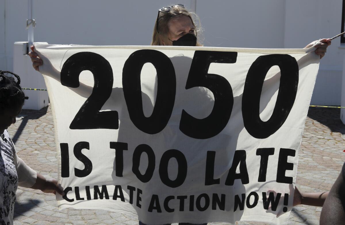 A protester holds a banner reading "2050 is too late - Climate action now!"
