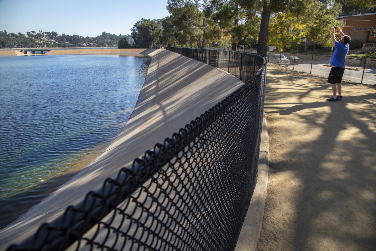 A jogger stops for a photo of the lake from the new Ivanhoe pedestrian path west of Silver Lake Reservoir.