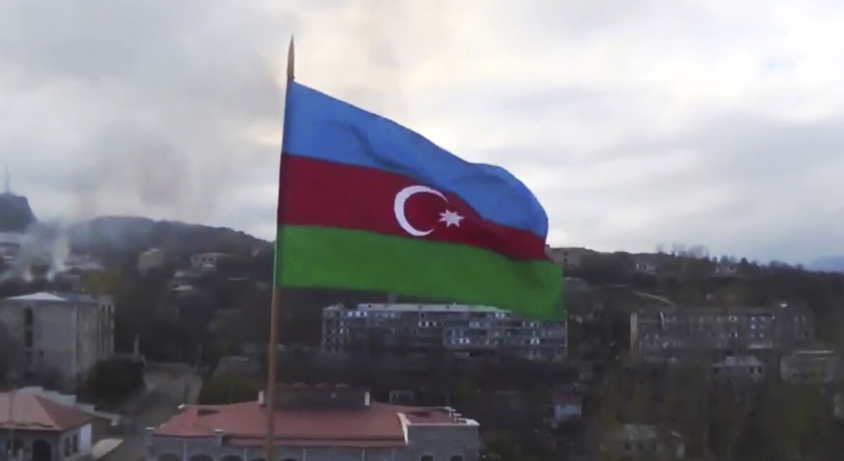 Azerbaijan's national flag with the city of Shushi in the background