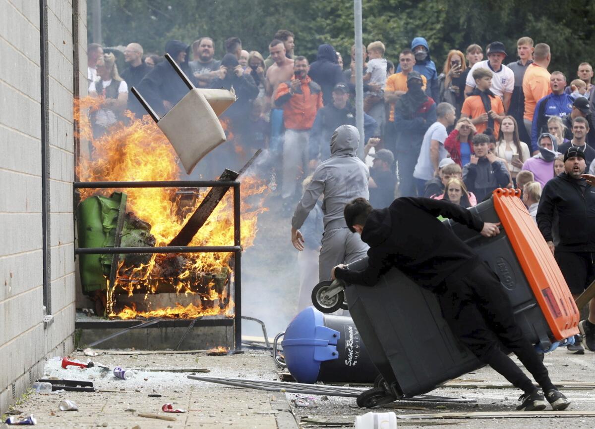 A crowd near a building with a fire set outside.