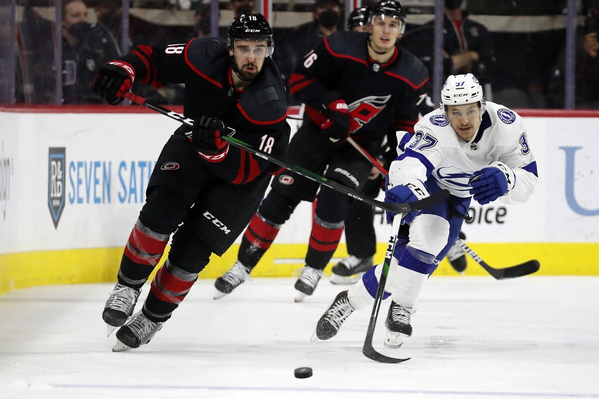Carolina Hurricanes' Cedric Paquette (18) and Tampa Bay Lightning's Yanni Gourde (37) chase the puck during the second period of Game 2 of an NHL hockey Stanley Cup second-round playoff series in Raleigh, N.C., Tuesday, June 1, 2021. (AP Photo/Karl B DeBlaker)