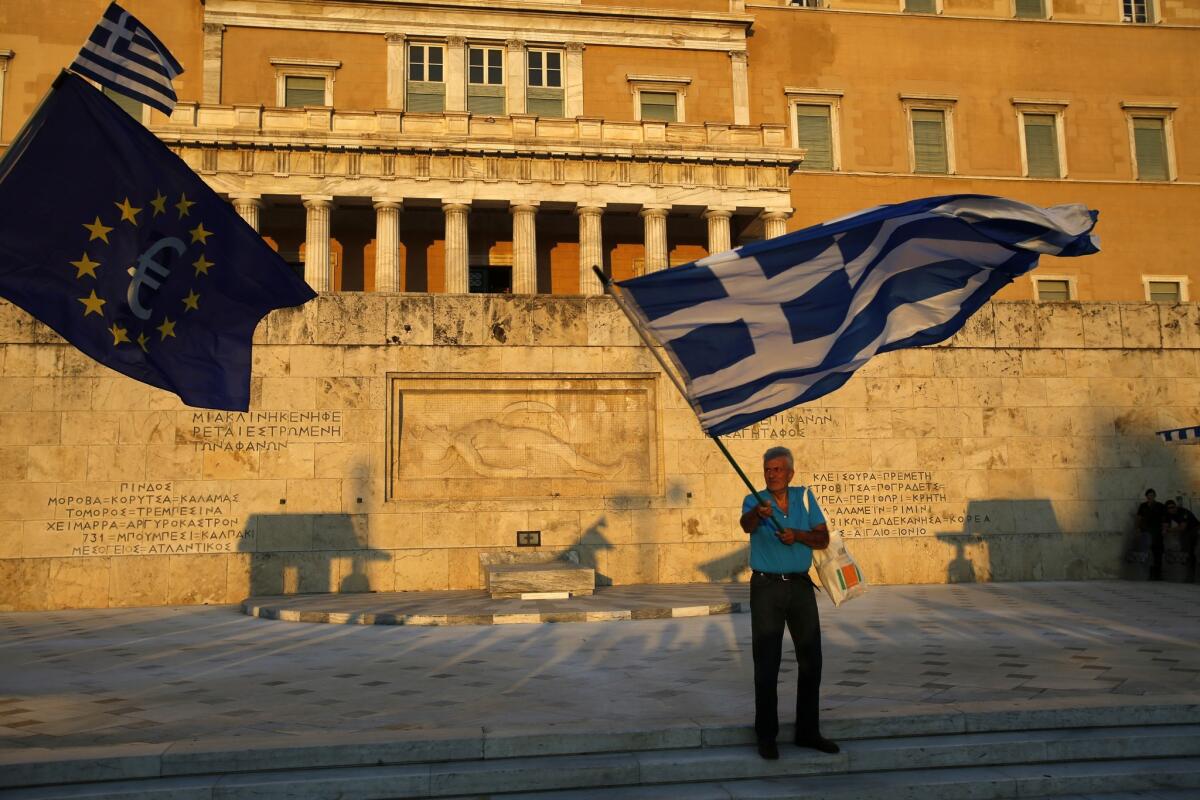 Pro-euro demonstrators wave a Greek flag, right, and a European Union flag in front of the Greek parliament during a rally Thursday at Syntagma square in Athens.