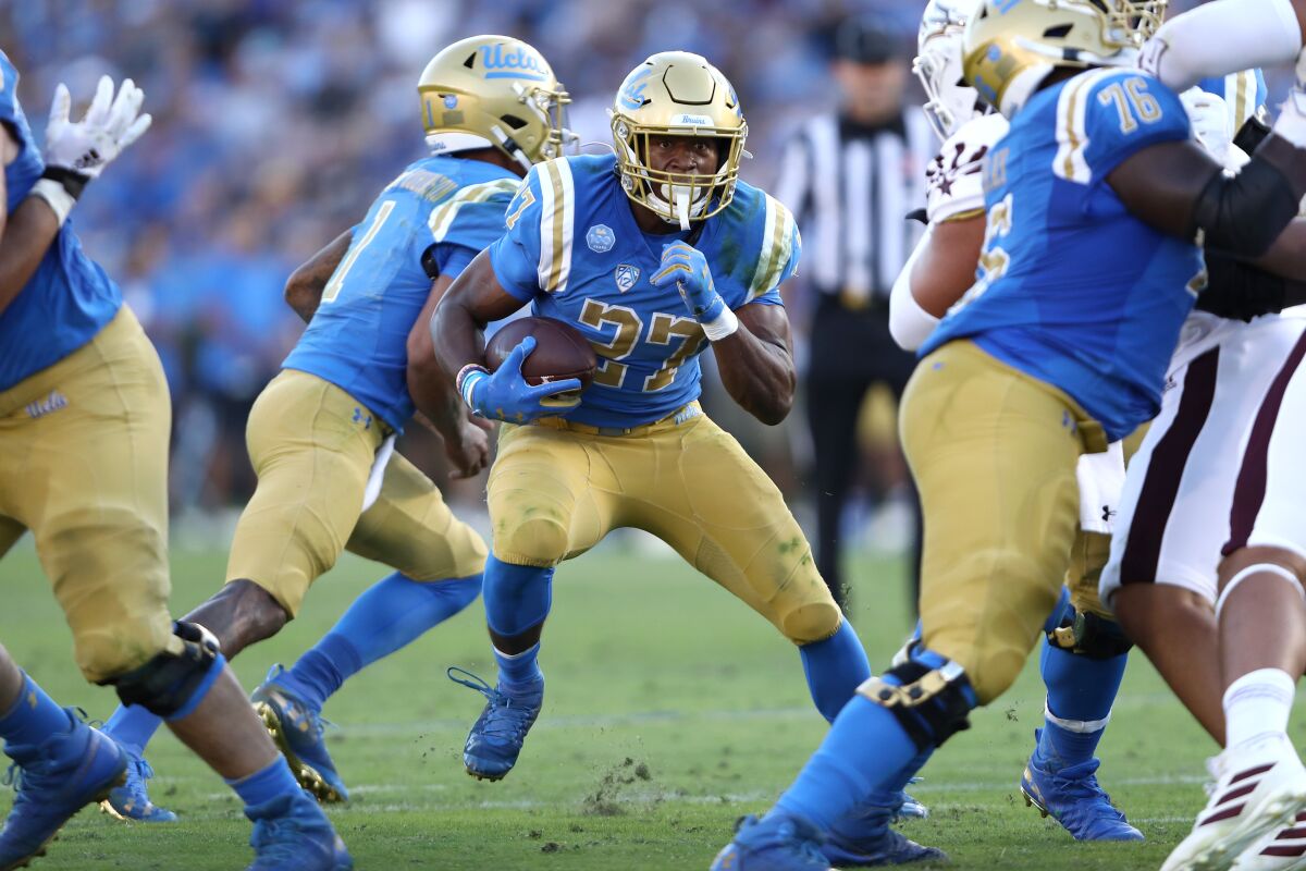 UCLA running back Joshua Kelley runs with the ball past Arizona State's Jermayne Lole for short yardage during the first half on Oct. 26, 2019 at the Rose Bowl.