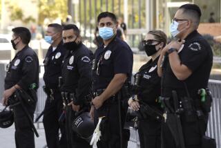 LOS ANGELES, CA - SEPTEMBER 18, 2021 - - Los Angeles police officers keep an eye on an anti-vaccine protesters rally along 1st Street in front of L.A.P.D. Headquarters in downtown Los Angeles on September 18, 2021. (Genaro Molina / Los Angeles Times)