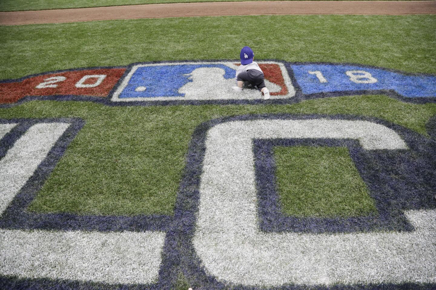 David Freese’s baby crawls over the NLCS logo as the team celebrates a 5-1 win over the Brewers.