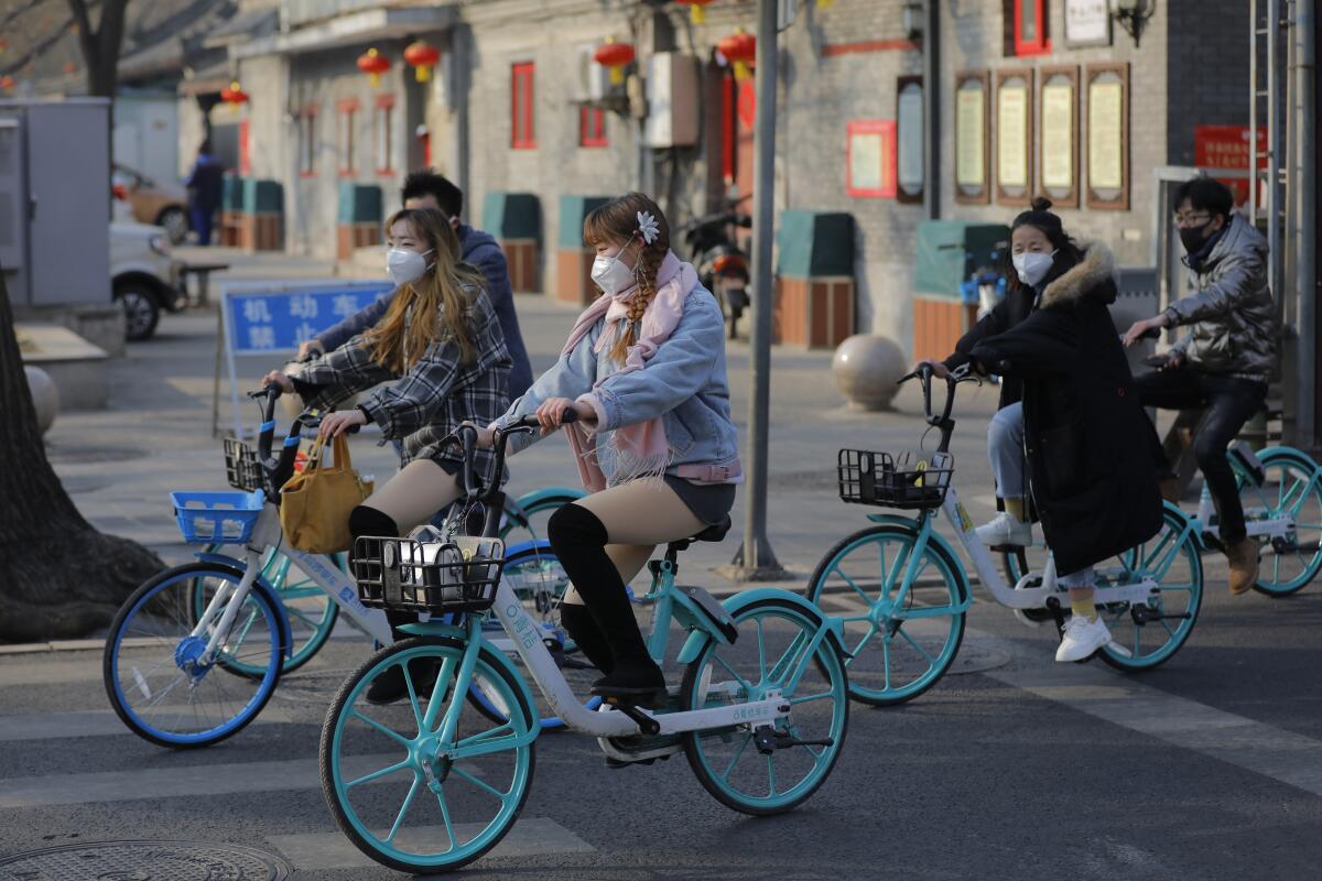 People wear masks riding bicycles outside Jingshan Park in Beijing last month.