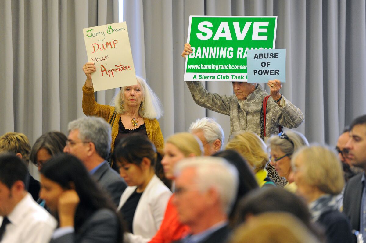 People hold protest signs Wednesday at the first California Coastal Commission hearing at the Santa Monica Civic Auditorium since the firing of Executive Director Charles Lester.