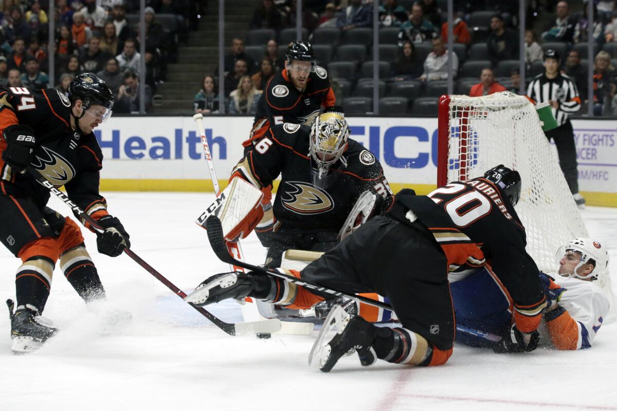 Islanders center Jordan Eberle gets hit to the ice by Ducks left wing Nicolas Deslauriers in front of goaltender John Gibson and center Sam Steelduring the first period of a game Nov. 25 at Honda Center.
