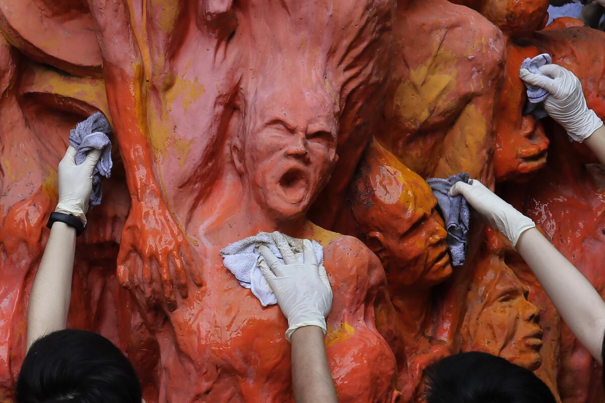 The sculpture with its anguished human forms is washed by Hong Kong students in a 2019 image