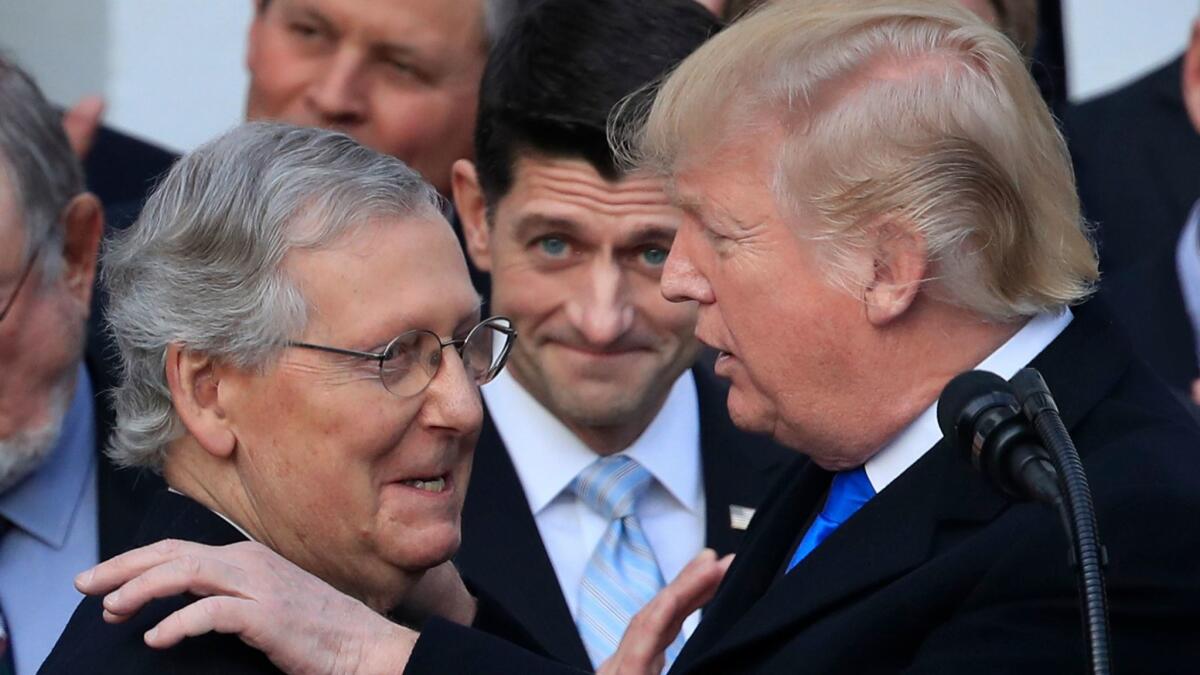 Donald Trump congratulates Senate Majority Leader Mitch McConnell, while House Speaker Paul Ryan watches, to acknowledge the final passage of tax overhaul legislation.
