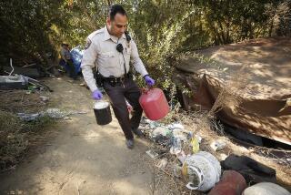 VAN NUYS, CA - NOVEMBER 4, 2019 City of Los Angeles Recreation and Parks Park Ranger Rami Al-Awar carries propane tanks found in one of many homeless encampments in the Sepulveda Basin Wildlife Reserve at Lake Balboa Anthony C. Beilenson Park in Van Nuys Monday morning as the third of a four-phase extensive City cleanup effort of homeless encampments at the Sepulveda Basin Wildlife Reserve continues in the San Fernando Valley. (Al Seib / Los Angeles Times)