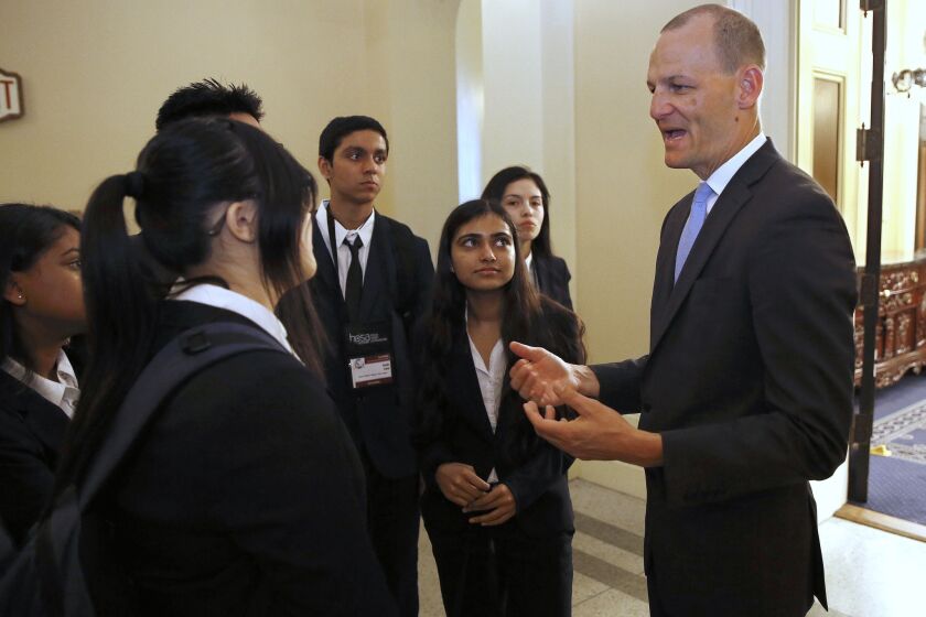 Assemblyman Kevin McCarty, D-Sacramento, right, talks with a group of high school students after his news conference concerning a proposed package of bills dealing with the recent college admissions scandal, Thursday, March 28, 2019, in Sacramento, Calif. McCarty, and other Democratic lawmakers unveiled a half-dozen measures that would require that three college administrators sign off on special admissions and a ban upon preferential admissions for students related to the institution's donors of alumni. (AP Photo/Rich Pedroncelli)