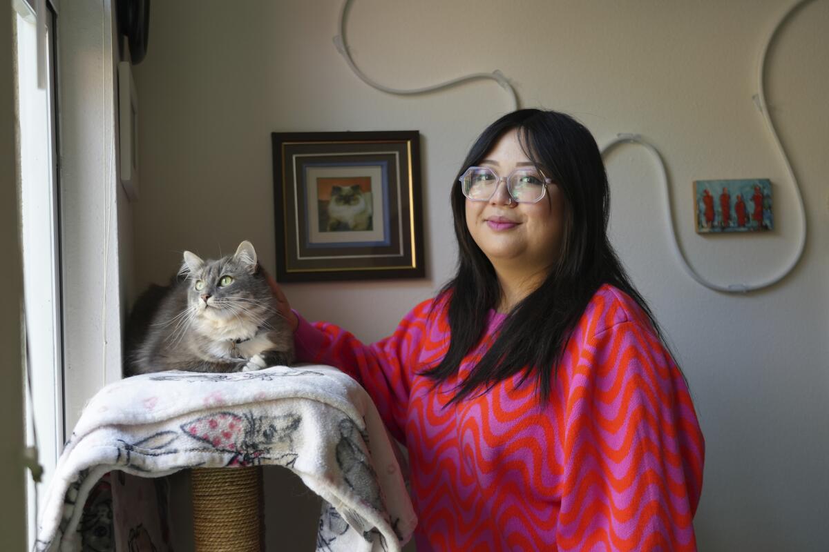 Celina Chanthanouvong stands with her cat in her apartment in Emeryville, Calif., on June 2, 2023. 